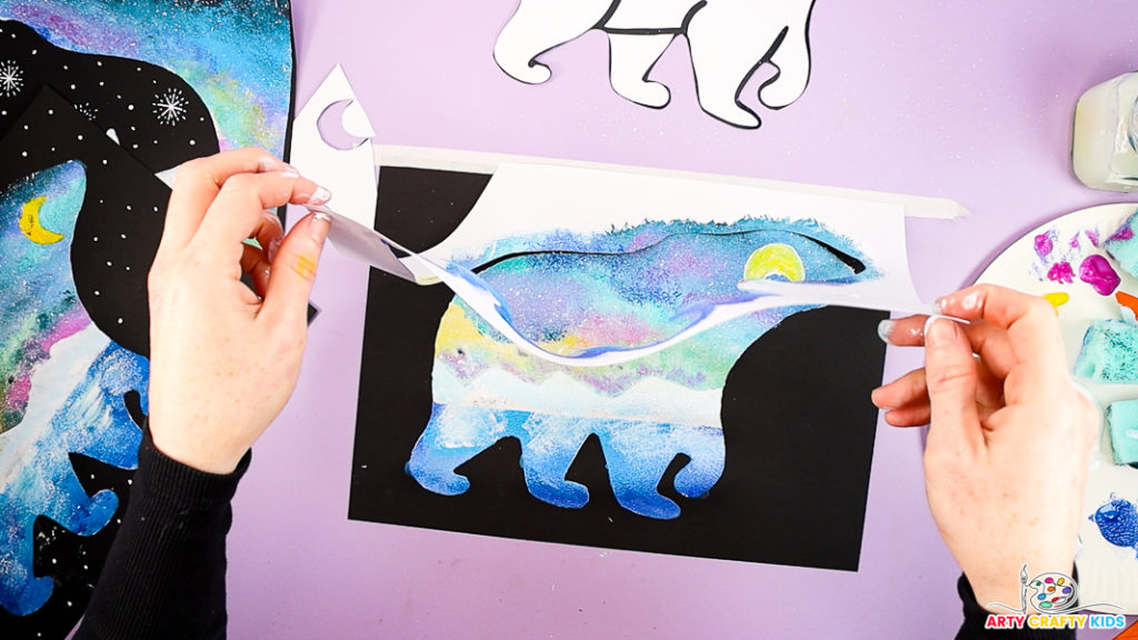 Image of a hand removing the template to reveal the painted polar bear silhouette.