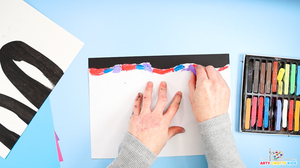 Image of a hand applying chalk blocks along the jagged edge of the paper.