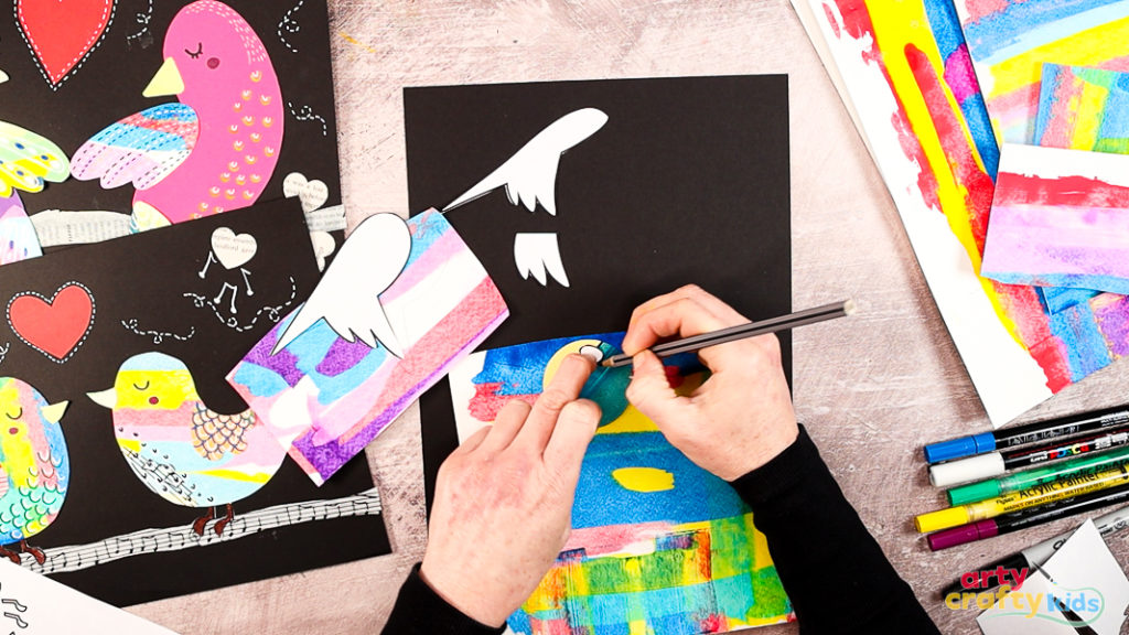 Image of a hand tracing the bird elements onto colorful painted paper.