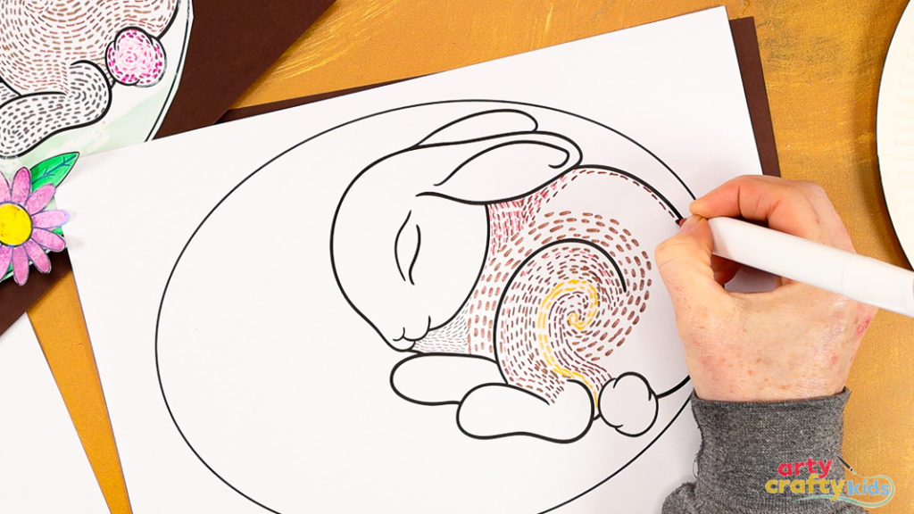 Image of a hand filling the bunny's back with dashed brown lines.