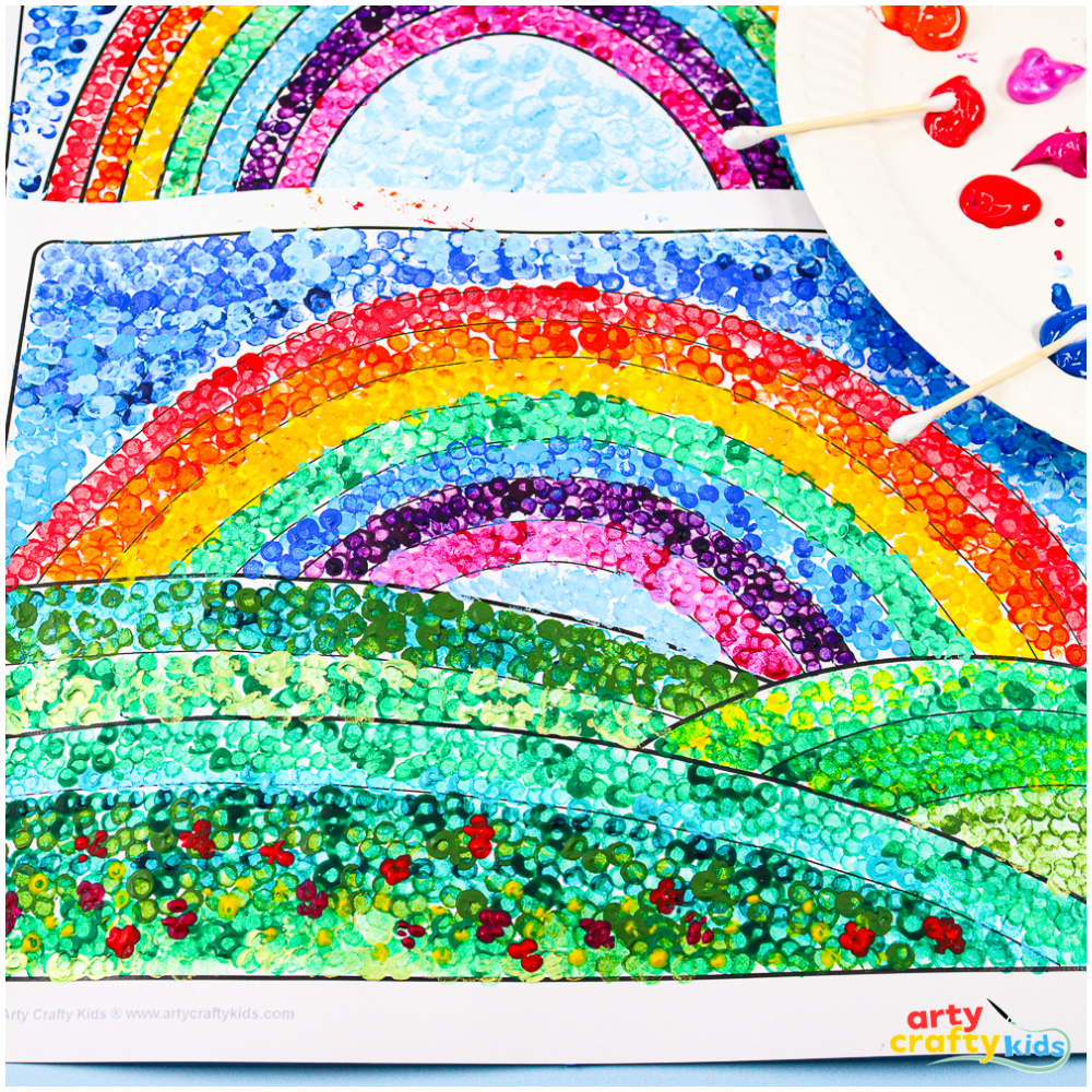 A close-up of a pointillism rainbow artwork, showing tiny, overlapping paint dots in red, orange, yellow, green, blue, and purple. The texture and layering create a vibrant, blended effect.